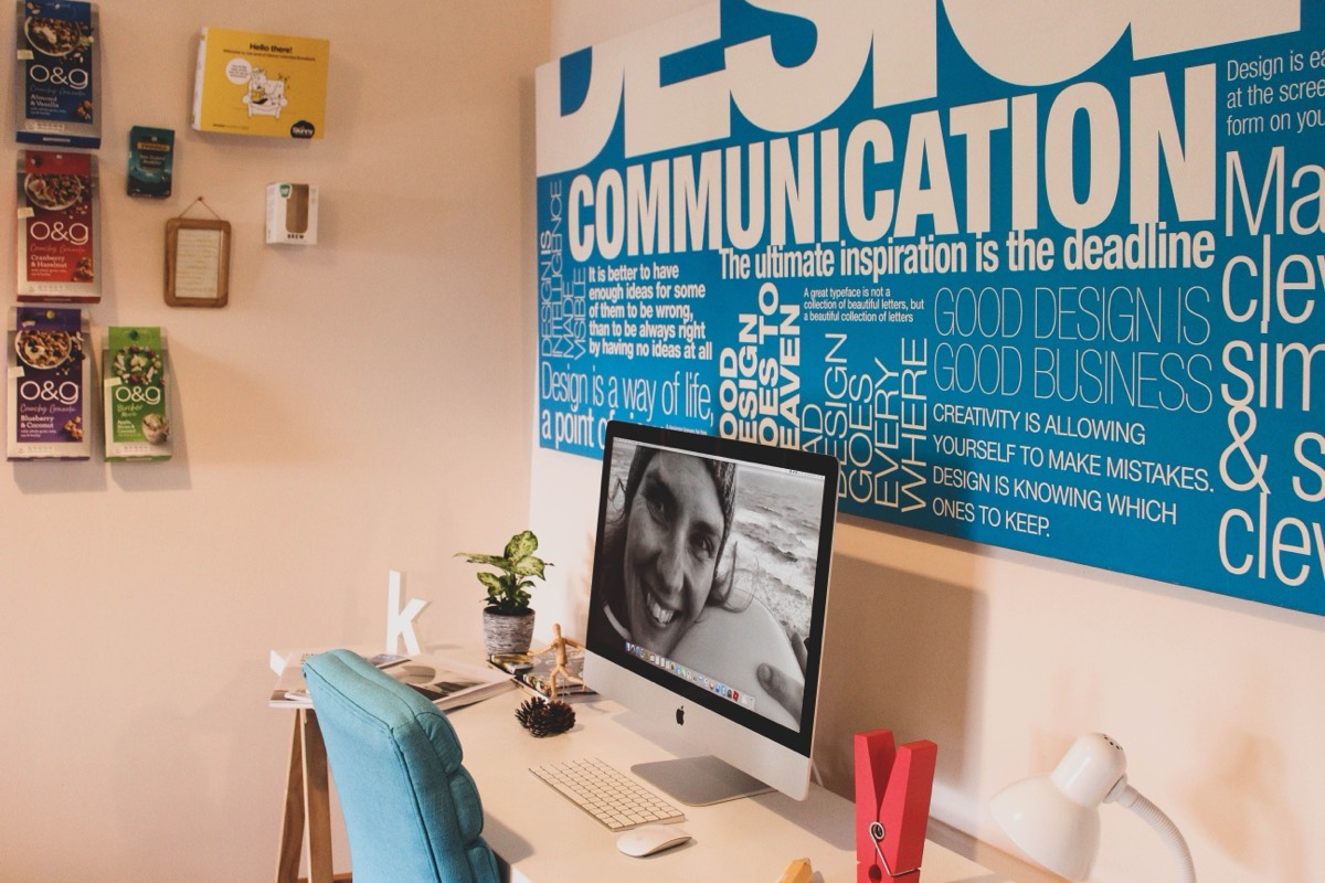 The Creoweb studio desk, with an iMac in front of a large typographic design poster